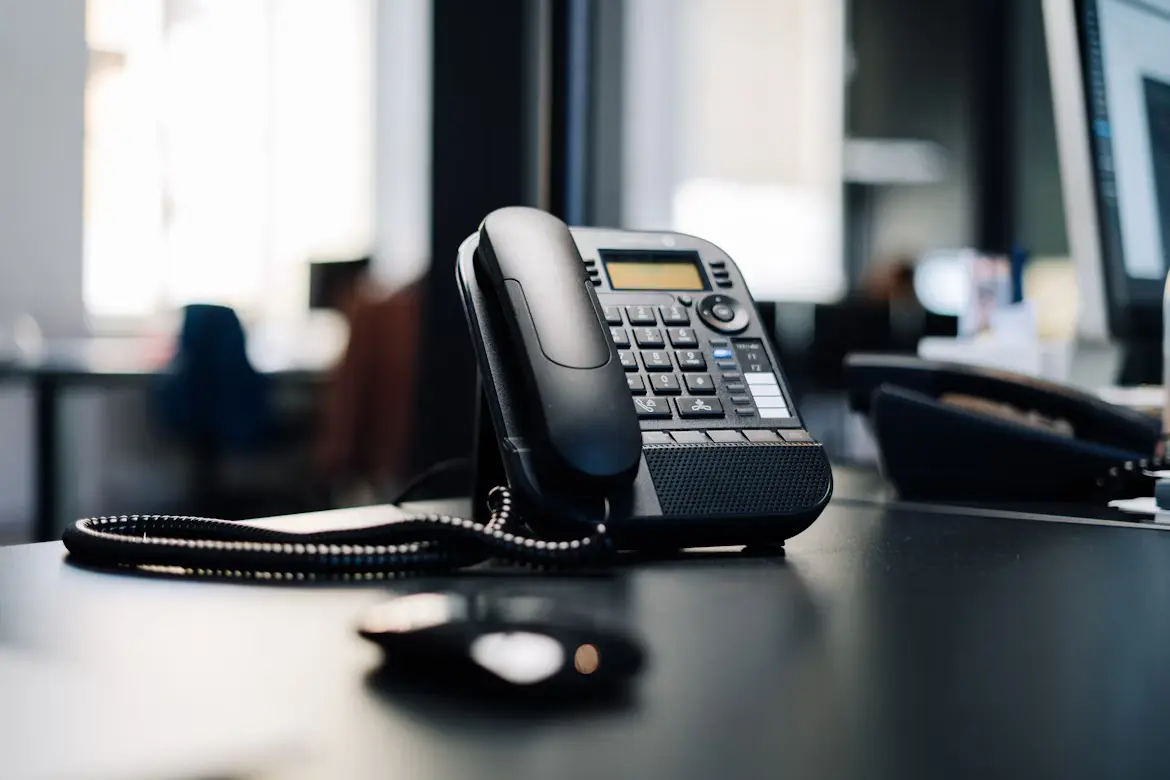 A modern office phone on a clean desk, ready to take a call.